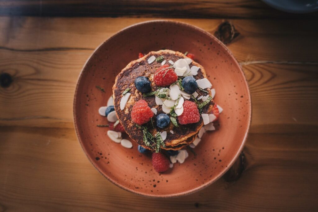 Pancake stack with raspberries, blueberries and almond flakes, seen from above