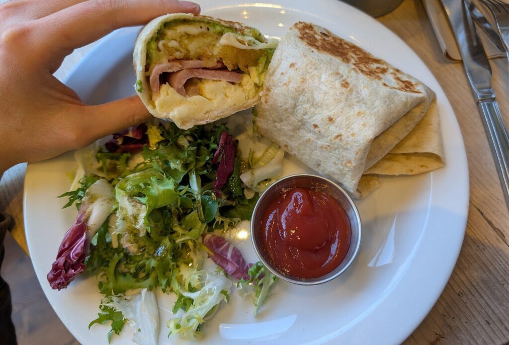 Halved breakfast wrap with ham and egg, salad and ketchup