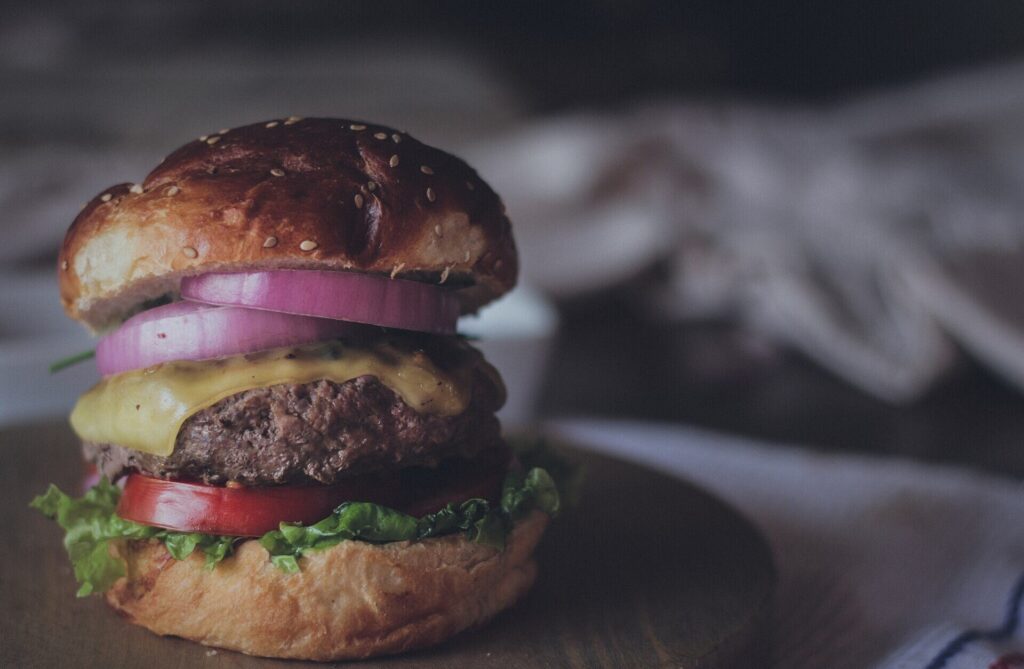 Cheeseburger with red onion, tomato and lettuce on a brioche bun