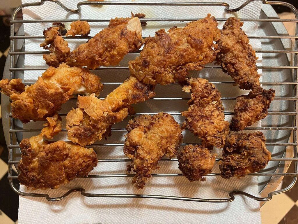 Homemade crispy chicken strips cooling on a wire rack