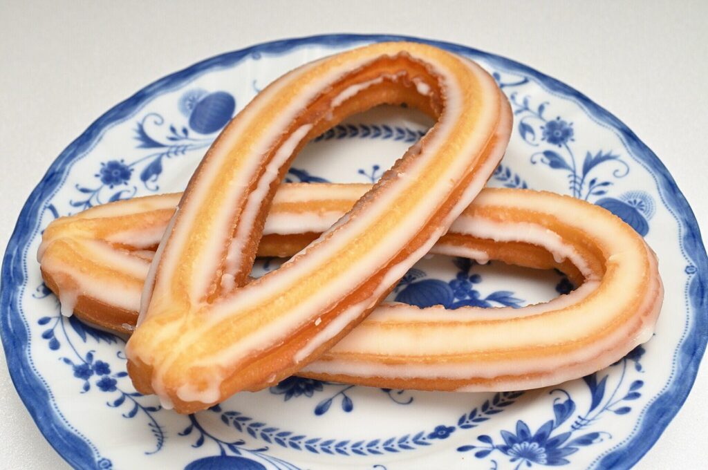 Two glazed fried-dough loops on a blue and white plate