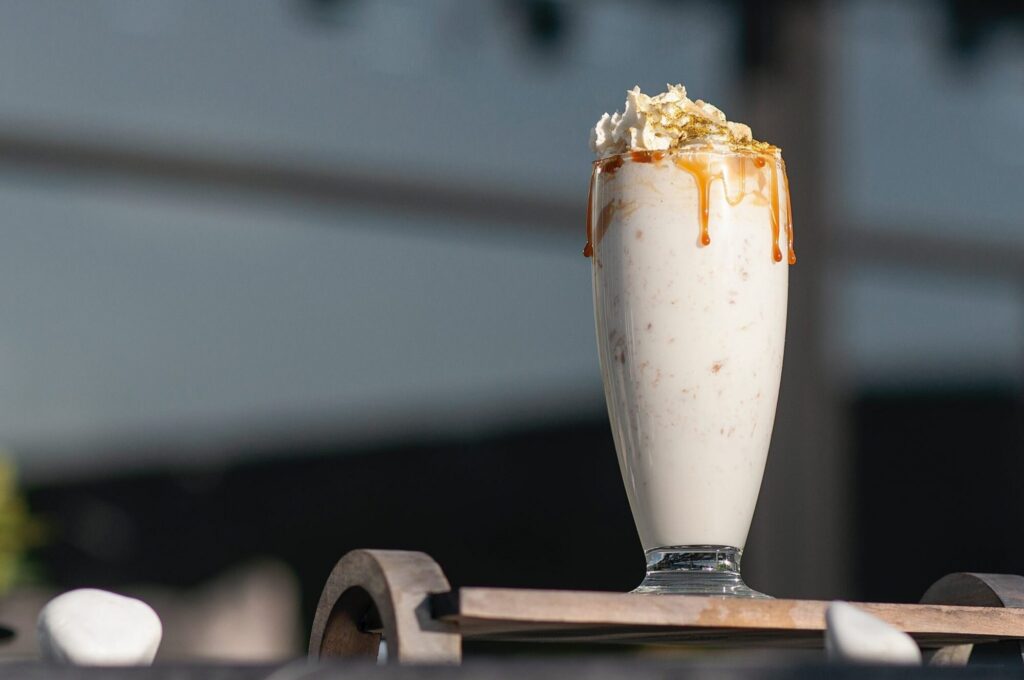 Tall vanilla milkshake with whipped cream and dripping caramel