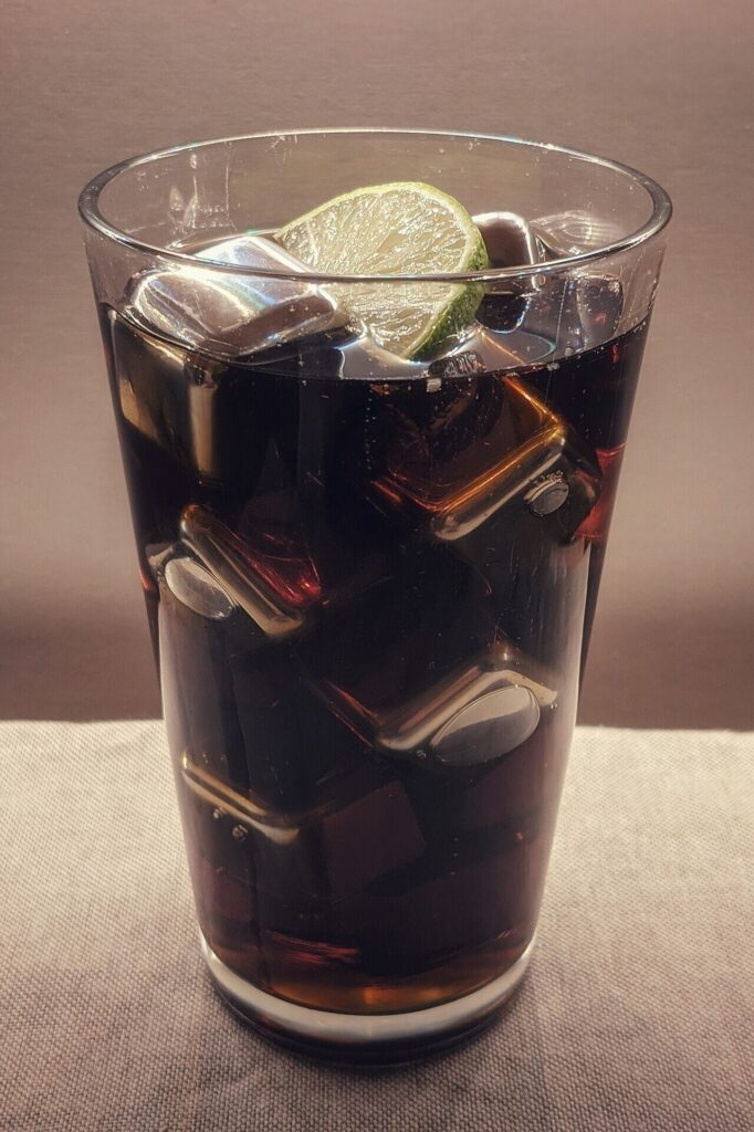 Glass of cola with ice and a lime wedge
