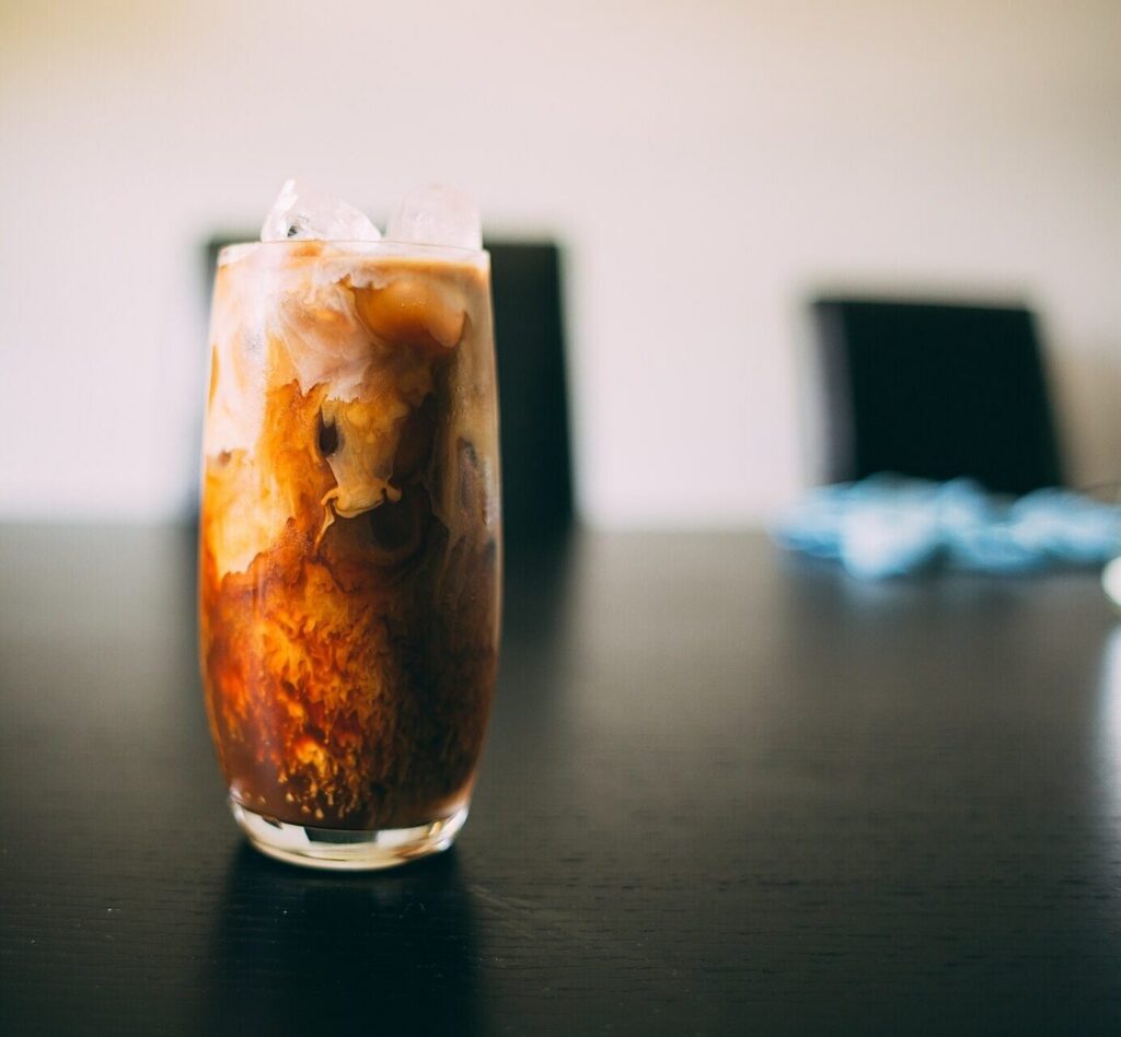 Iced coffee with milk swirling through a tall glass