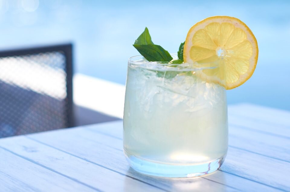 Lemonade on ice with basil and a lemon wheel on a terrace table