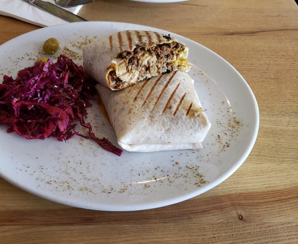 Toasted wrap with spiced beef next to red cabbage slaw