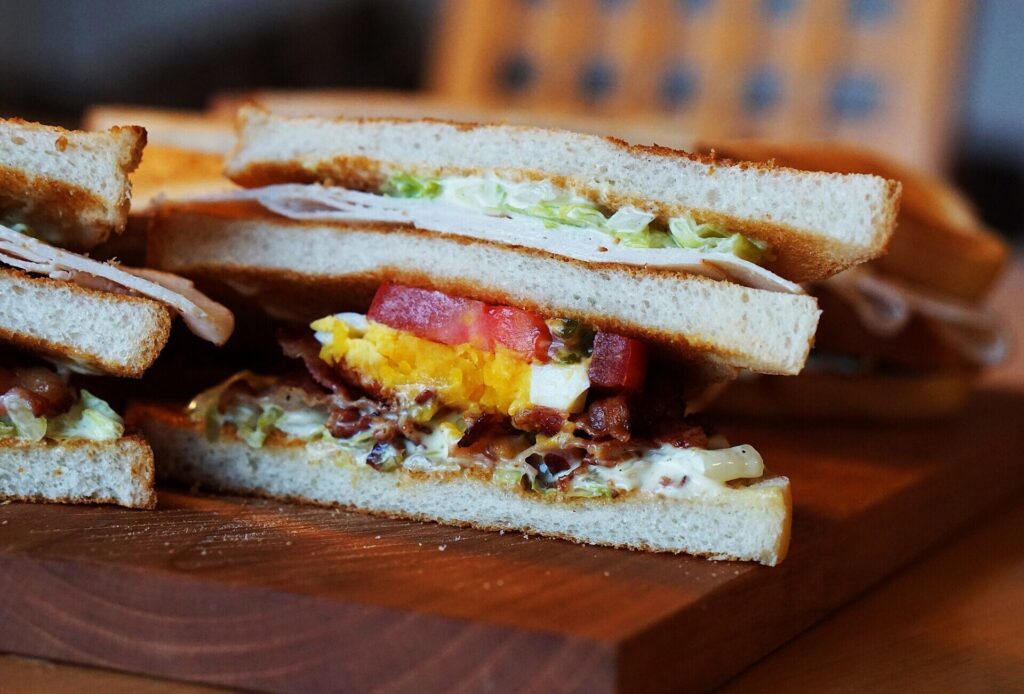 Club sandwich with turkey, bacon, egg and tomato on a board