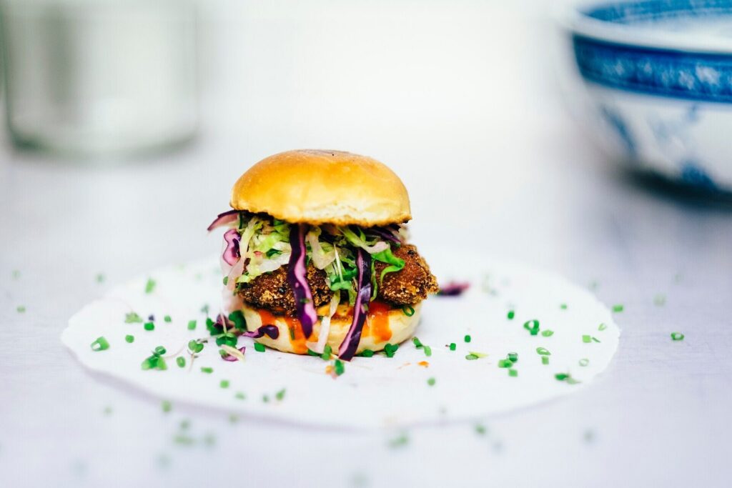 Crispy chicken slider piled with red cabbage slaw on paper
