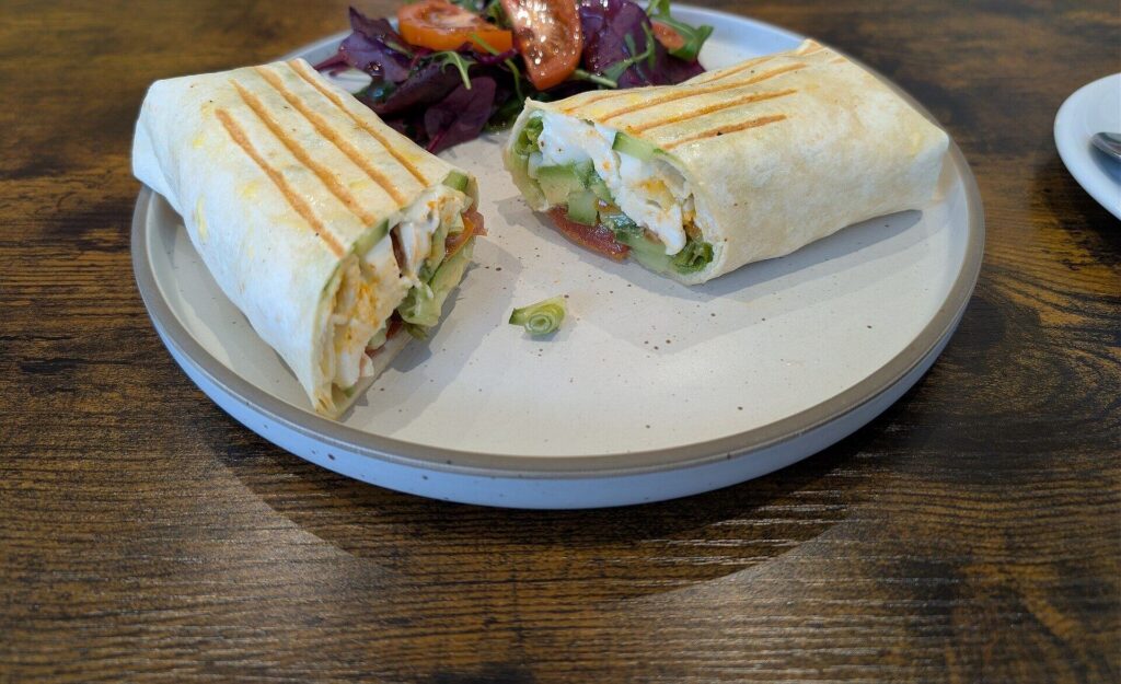 Grilled wrap cut in half with a side salad on a wooden table