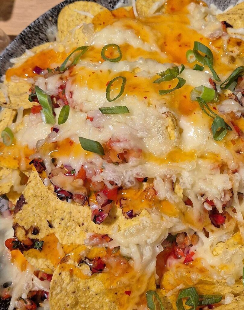 Nachos with melted cheese, pico de gallo and spring onions